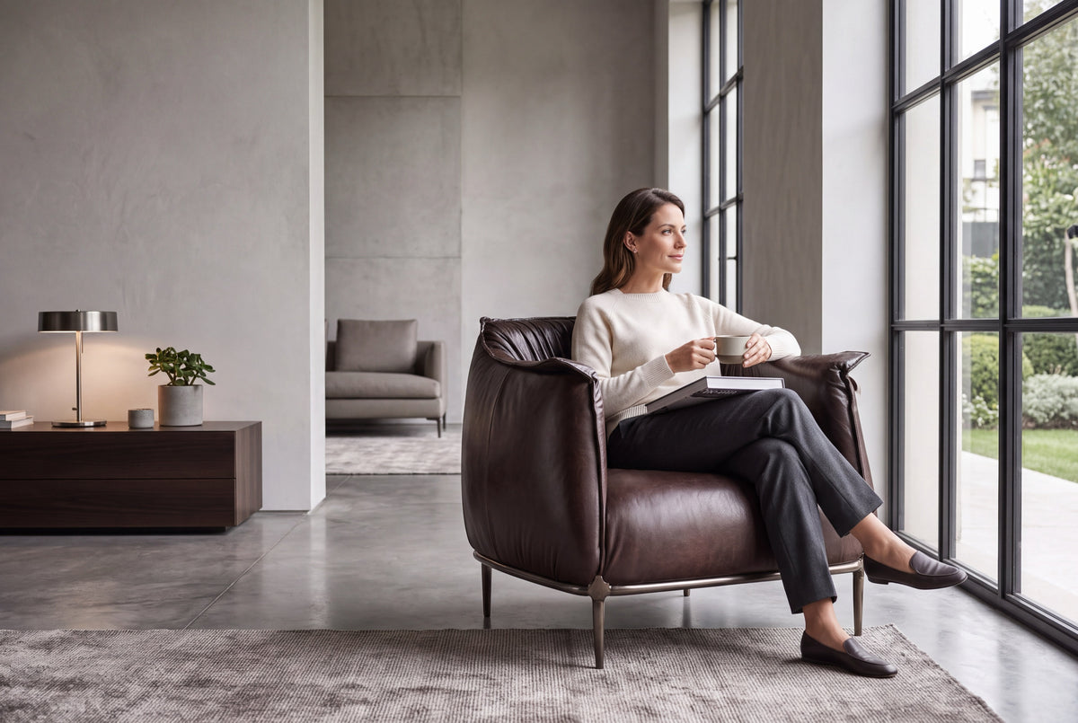 Woman relaxing in the Amon armchair in dark brown leather